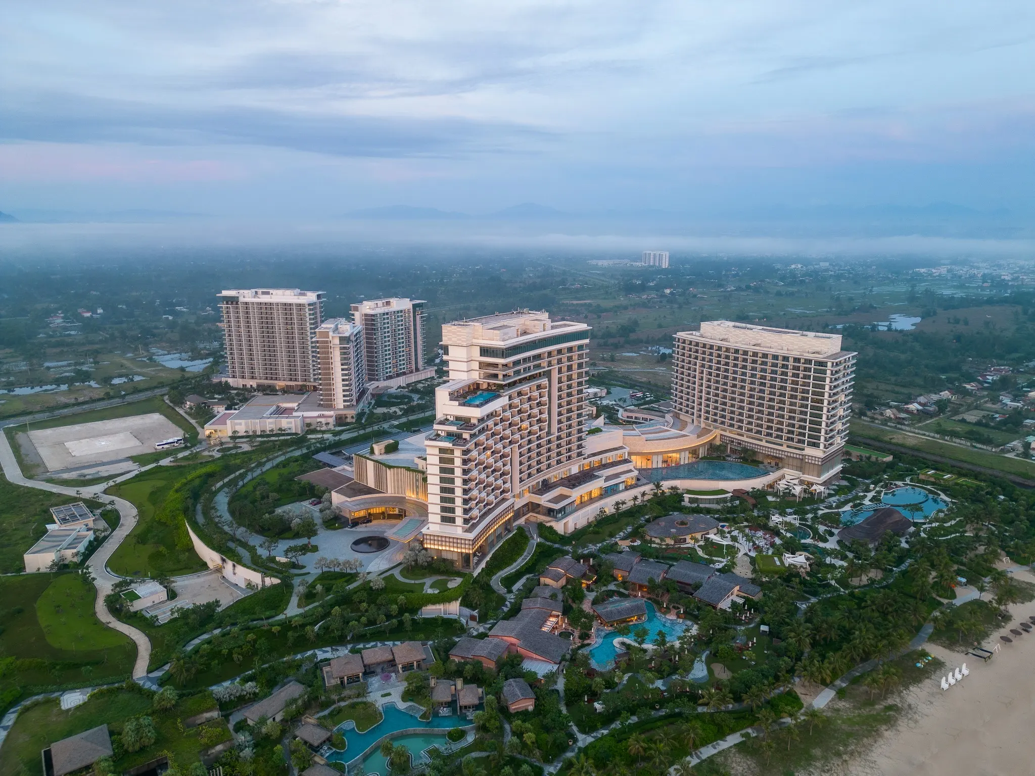 Ảnh chụp một resort tổ chức kỷ niệm ngày cưới với không gian lãng mạn bên bờ biển, trang trí bằng hoa tươi, nến và ánh đèn ấm áp, tạo nên bầu không khí ấm cúng và đáng nhớ cho các cặp đôi.