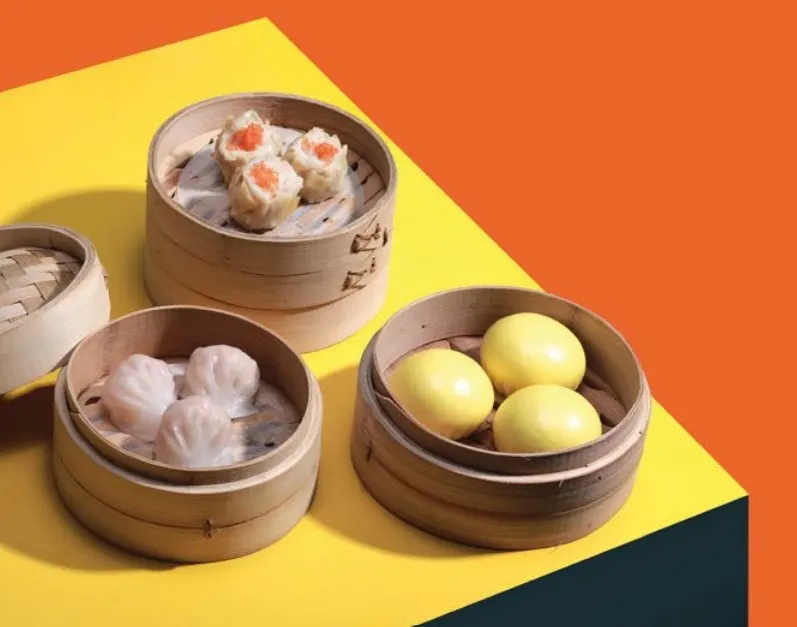 一張美食特寫照片，展示會安中式餐廳內多道精緻的港式點心，包括燒賣、蝦餃與叉燒包，色香味俱全，令人垂涎