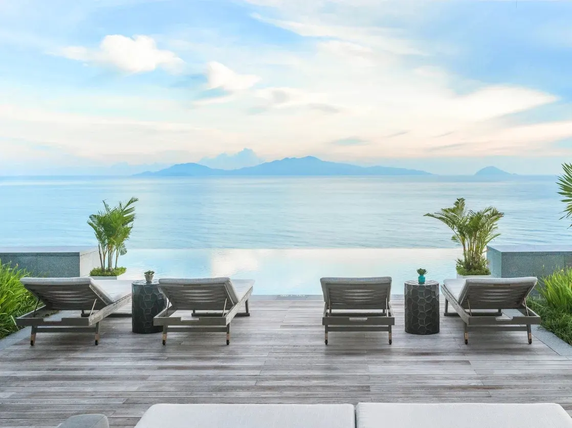 Ảnh chụp một resort có bể bơi vô cực tại Việt Nam, nằm giữa khung cảnh thiên nhiên tuyệt đẹp với hồ bơi kéo dài ra tận chân trời, tạo cảm giác như hòa mình vào biển cả.